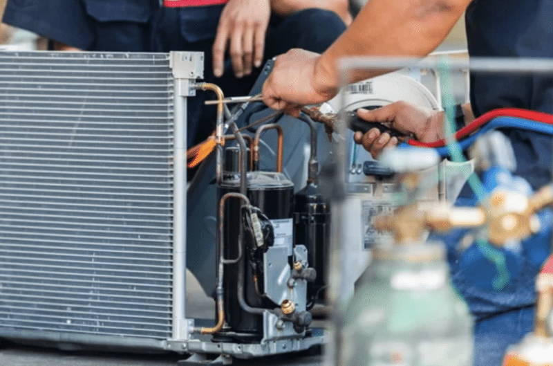 A close up of a the hands of an HVAC tech working on an outdoor unit.