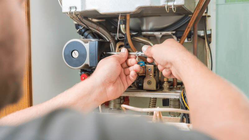 An HVAC technician repairing a gas furnace